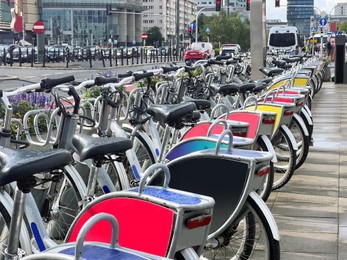 Many bicycles parked outdoors. Bike rental service
