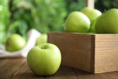 Photo of Fresh ripe green apple on wooden table against blurred background
