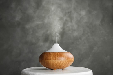 Modern essential oil diffuser on white table against grey background