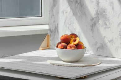 Bowl of juicy peaches and double-sided backdrop on table in photo studio. Space for text