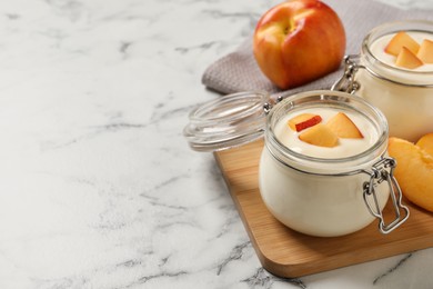Delicious yogurt with fresh peach on white marble table, space for text