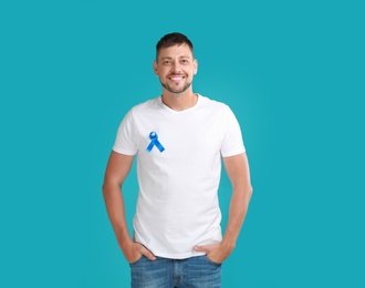 Photo of Man with blue ribbon on turquoise background. Urology cancer awareness