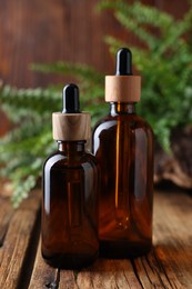 Photo of Glass bottles of essential oil on wooden table, closeup