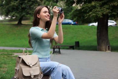 Photo of Young woman with camera taking photo in park. Interesting hobby