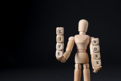 Life work balance concept. Wooden mannequin holding cubes on black background, space for text