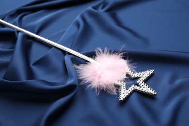 Beautiful silver magic wand with feather on blue fabric