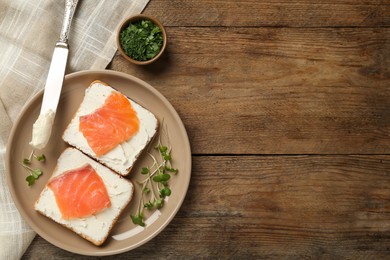 Photo of Delicious sandwiches with cream cheese and salmon on wooden table, flat lay. Space for text