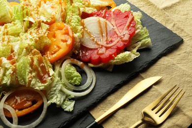 Photo of Delicious salad with Chinese cabbage, tomatoes and onion served on black table, closeup