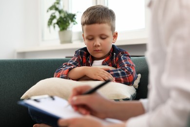 Psychologist working with unhappy little boy in office. Mental health problems