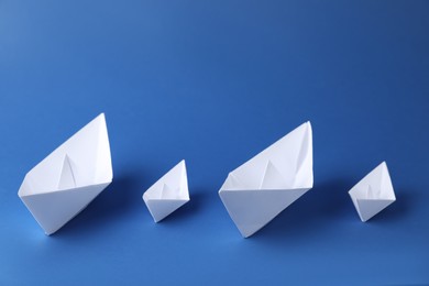 Handmade paper boats on blue background. Origami art