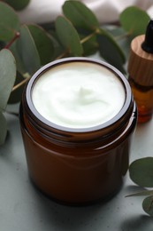 Photo of Jar of hand cream and eucalyptus branches on plate, closeup