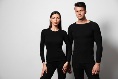 Couple wearing thermal underwear on light grey background. Space for text