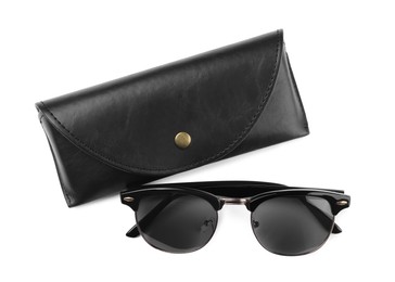 Modern sunglasses and black case on white background, top view