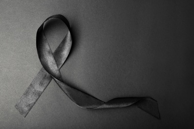 Black ribbon and space for text on dark background, top view. Funeral accessory