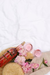 Flat lay composition with beautiful peonies and rose wine on white fabric, space for text