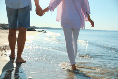 Young couple walking on beach near sea, closeup. Honeymoon trip
