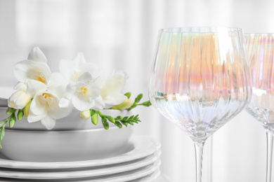 Set of glasses and dishes with flowers on light background, closeup