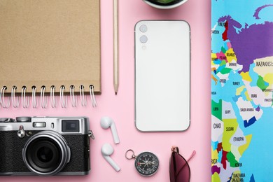 Flat lay composition with modern smartphone and travel items on pink background