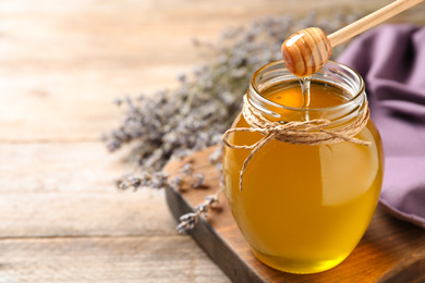 Photo of Tasty fresh sunflower honey with wooden dipper on table, closeup