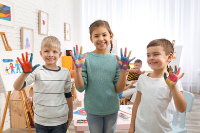Cute little children with painted palms in room