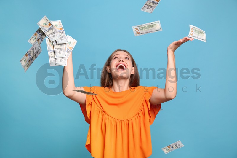 Portrait of happy lottery winner under money rain on light blue background