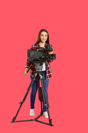 Operator with professional video camera on pink background