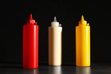 Ketchup, mustard and mayonnaise in squeeze bottles on grey table