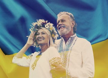 Double exposure of happy mature couple wearing national clothes and Ukrainian flag