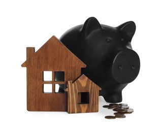 Photo of Piggy bank, wooden house models and coins on white background. Saving money concept