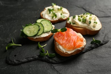 Photo of Delicious sandwiches with cream cheese and other ingredients on black table