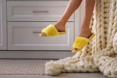 Woman in fuzzy slippers at home, closeup. Weekend morning