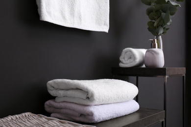 Clean soft towels on stand near black wall