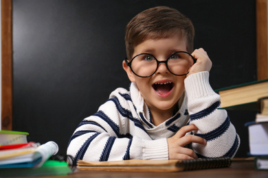 Cute little child wearing glasses at desk in classroom. First time at school