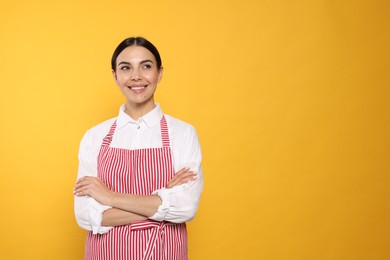 Photo of Young woman in red striped apron on yellow background, space for text