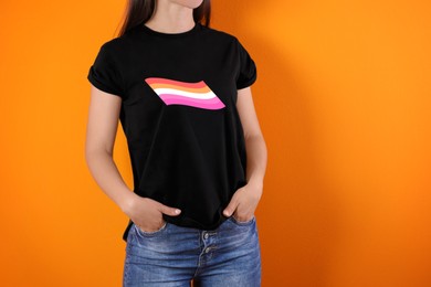 Young woman wearing black t-shirt with lesbian flag on orange background. LGBT concept