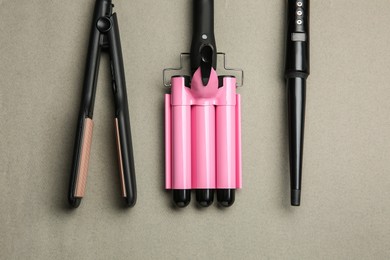 Photo of Set of modern hair irons on grey background, flat lay