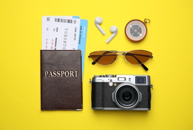 Flat lay composition with passport, tickets and travel items on yellow background