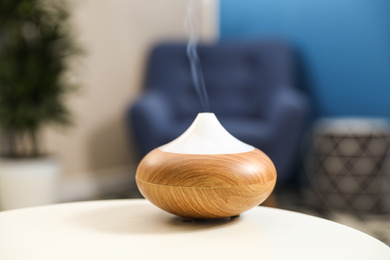 Photo of Aroma oil diffuser on white table at home. Air freshener