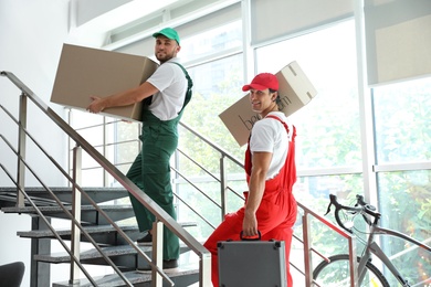 Male movers carrying boxes in new house