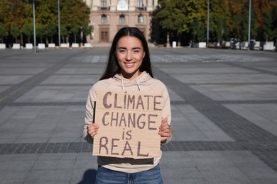 Young woman with poster protesting against climate change on city street