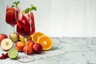 Delicious Red Sangria and fruits on white marble table, space for text