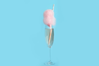 Photo of Cocktail with cotton candy in glass on light blue background