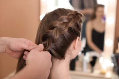 Photo of Professional hairdresser working with client in beauty salon, closeup