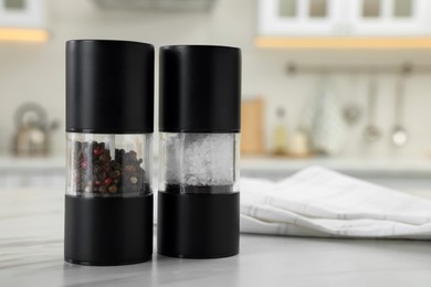 Salt and pepper mills with napkin on white marble table in kitchen. Space for text