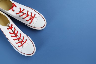 Photo of Pair of trendy sneakers on blue background, flat lay. Space for text