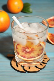 Delicious refreshing drink with sicilian orange, fresh fruits and green leaves on light blue wooden table