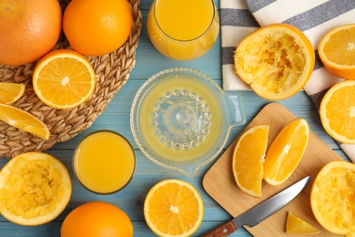 Freshly made juice, oranges and squeezer on blue wooden table, flat lay