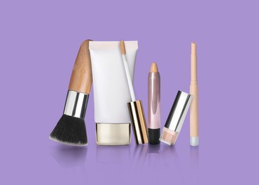 Set with different decorative cosmetics on violet background. Luxurious makeup products