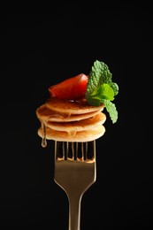 Fork with cereal pancakes, strawberry and mint on black background