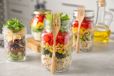 Glass jars with healthy meal on light grey marble table